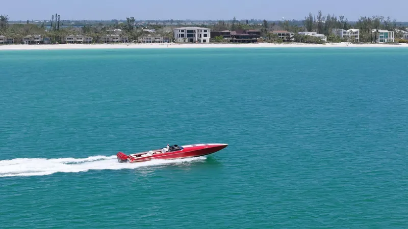 Slide: The Image of Red 2023 Nor-Tech 55 Flyer speedboat cruising on turquoise water near a sandy beach. - 3