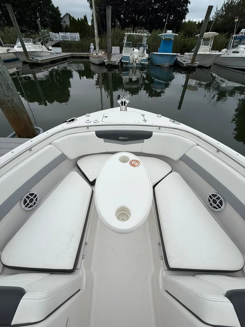 Slide: The Image of 2022 Robalo R247 Dual Console boat interior with white seating and table, docked in marina. - 12