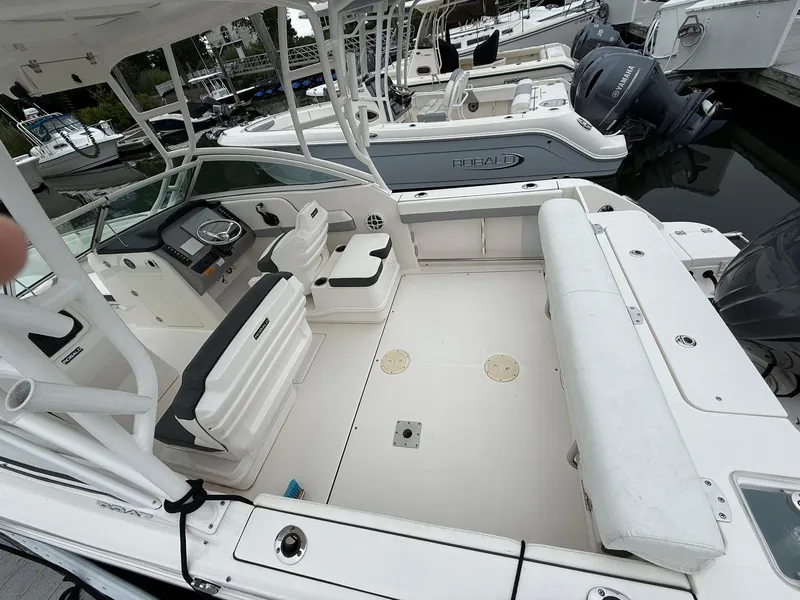 Slide: The Image of 2022 Robalo R247 Dual Console boat interior with seating and helm, docked at marina. - 2