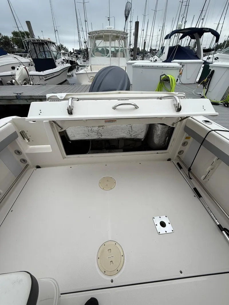Slide: The Image of 2022 Robalo R247 Dual Console boat interior at marina, open storage compartment. - 4