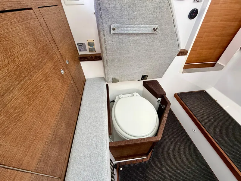 Slide: The Image of 2019 Axopar AX37XC boat interior with compact toilet and wooden cabinetry. - 19