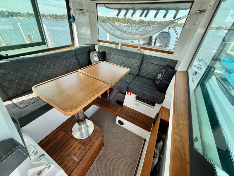 Slide: The Image of 2019 Axopar AX37XC interior with wooden table, cushioned seating, and scenic water view. - 22