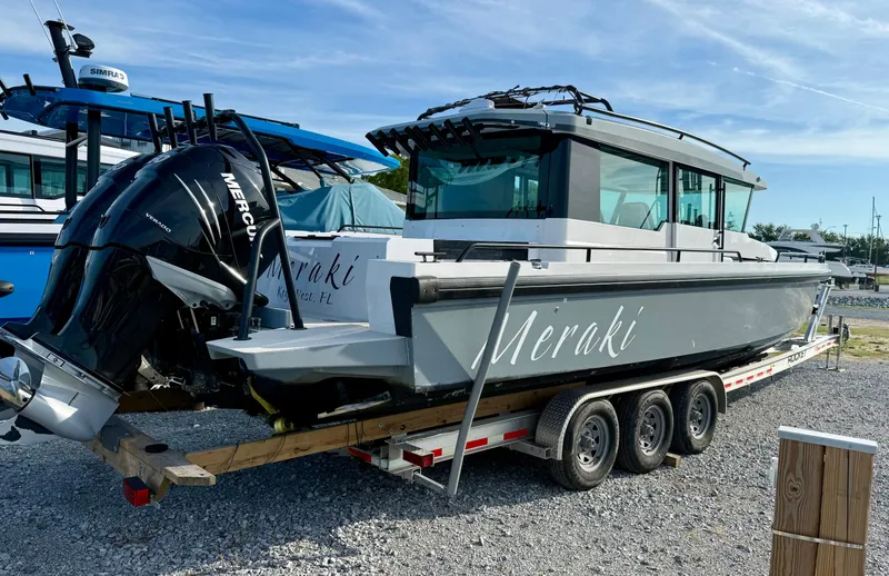 Slide: The Image of 2019 Axopar AX37XC boat on trailer with Mercury engine, labeled "Meraki," parked on gravel. - 6