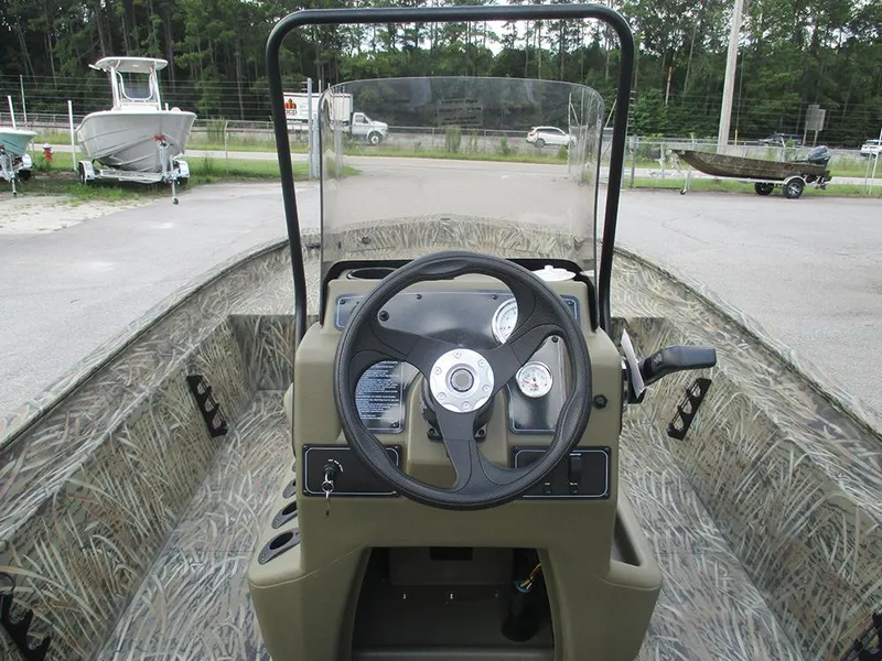 Slide: The Image of 2026 Tracker Grizzly 1860 CC boat interior with steering wheel and camouflage design. - 17