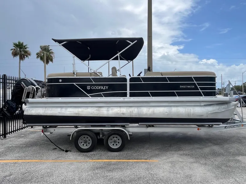 The Image of 2022 Godfrey Sweetwater 2286 FS pontoon boat on trailer, parked outdoors. - 0