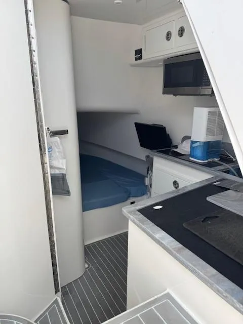 Slide: The Image of 2021 Contender 39 Fisharound cabin interior with bed, kitchenette, and modern amenities. - 20