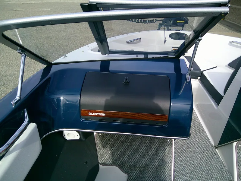 Slide: The Image of 2015 Glastron GT 180 Ski & Fish boat dashboard with open windshield and control panel. - 12