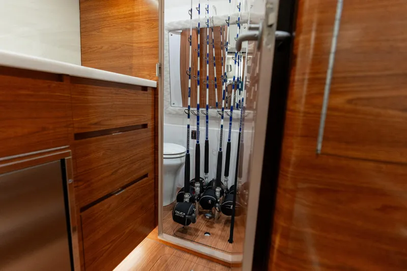 Slide: The Image of Interior of 2026 Phenom 43 Center Console with fishing rods and wooden cabinetry. - 9