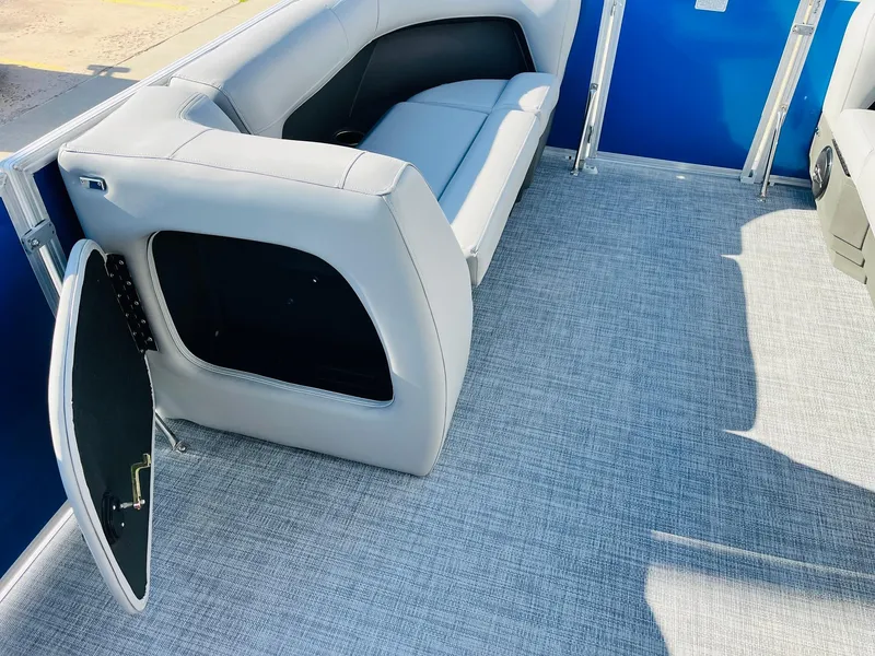 Slide: The Image of 2026 Sun Tracker Party Barge 18 DLX interior with gray seating and open storage compartment. - 13