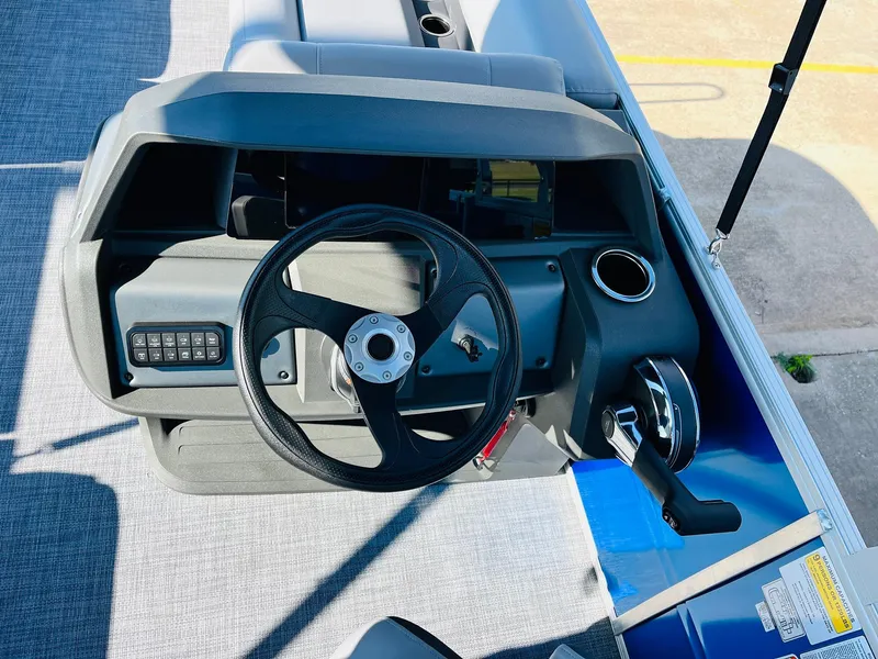 Slide: The Image of 2026 Sun Tracker Party Barge 18 DLX steering console with controls and cup holder. - 26