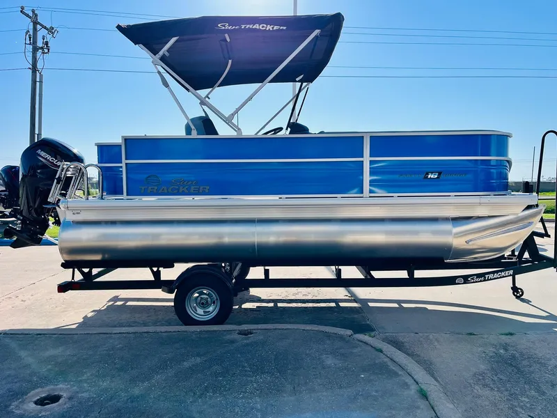 Slide: The Image of 2026 Sun Tracker Party Barge 18 DLX pontoon boat on trailer, blue and silver design. - 5