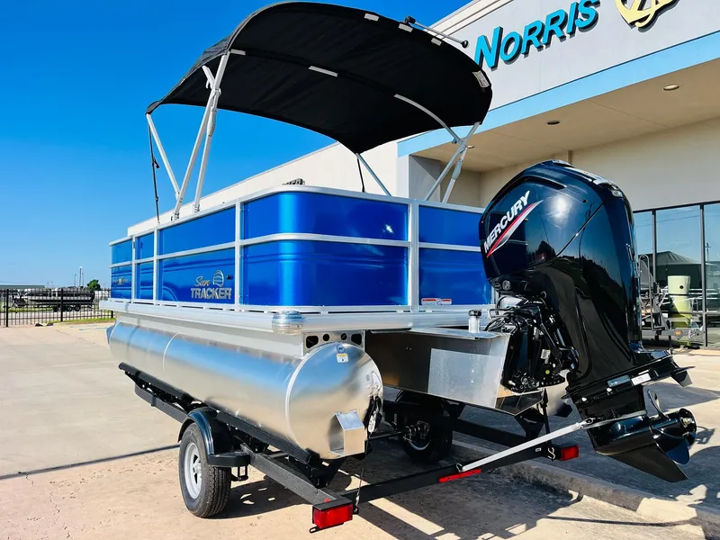 Slide: The Image of 2026 Sun Tracker Party Barge 18 DLX pontoon boat with Mercury engine, parked outside dealership. - 8