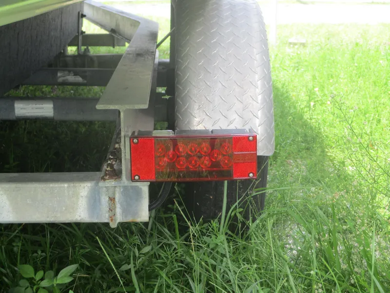 Slide: The Image of Trailer light and wheel of a 2008 Hydra-Sports 23 Bay Bolt in grassy area. - 21