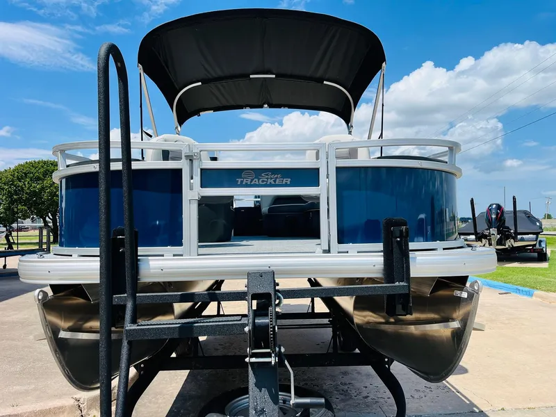 Slide: The Image of 2026 Sun Tracker Bass Buggy 18 DLX pontoon boat on trailer under blue sky. - 3