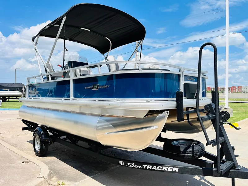 Slide: The Image of 2026 Sun Tracker Bass Buggy 18 DLX pontoon boat on trailer, under blue sky. - 4