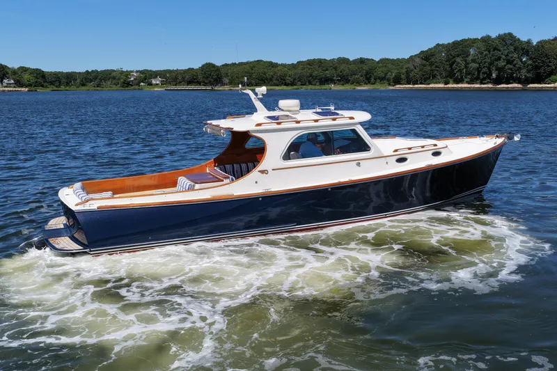 Slide: The Image of 2005 Hinckley 36 yacht cruising on a serene lake under a clear blue sky. - 10