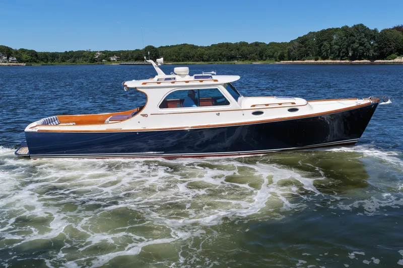 Slide: The Image of 2005 Hinckley 36 yacht cruising on a serene lake under a clear blue sky. - 11