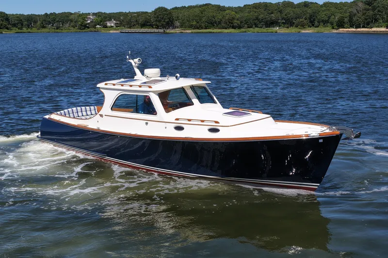 Slide: The Image of 2005 Hinckley 36 boat cruising on a calm lake with lush green shoreline. - 12