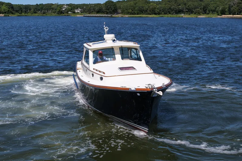Slide: The Image of 2005 Hinckley 36 boat cruising on a scenic lake with lush green shoreline. - 14