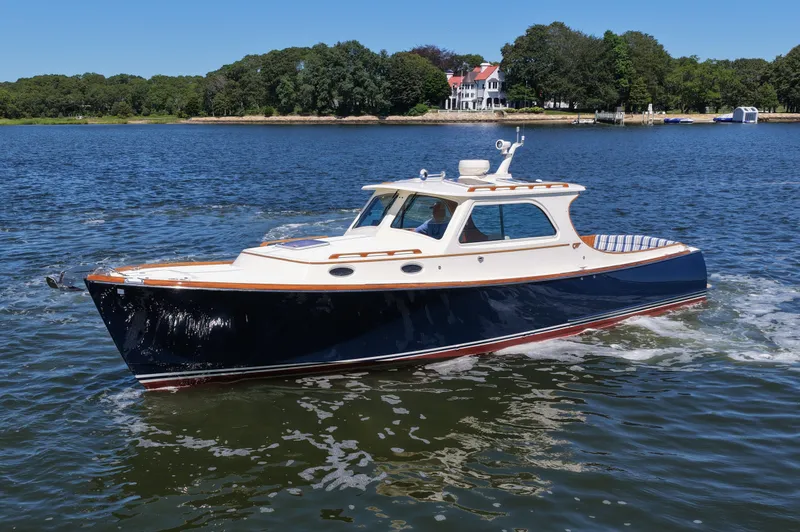 Slide: The Image of 2005 Hinckley 36 boat cruising on a scenic lake with a shoreline view. - 2