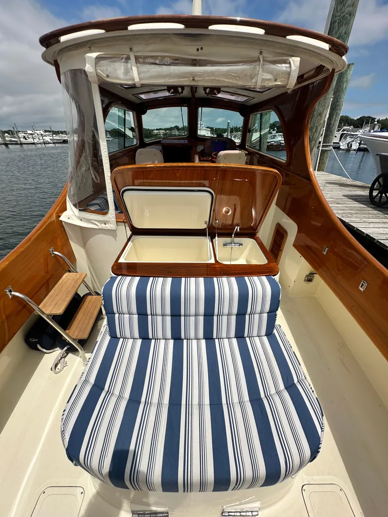 Slide: The Image of 2005 Hinckley 36 boat interior with striped seating and wooden accents at a marina. - 22