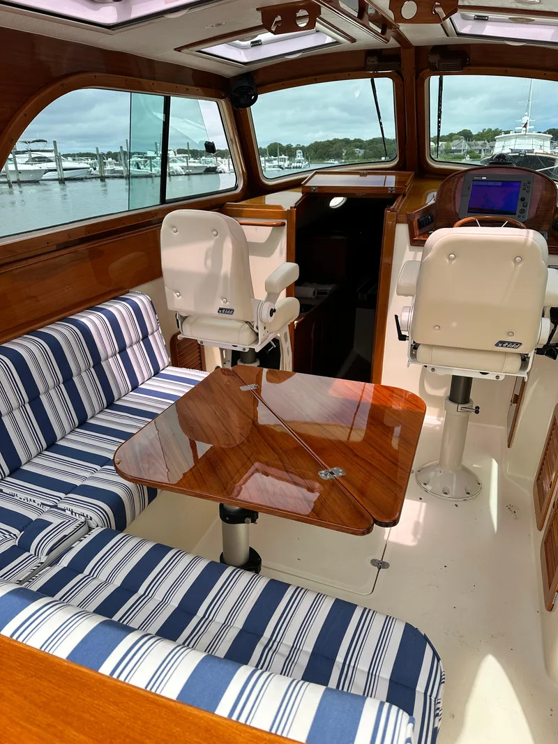 Slide: The Image of Interior of a 2005 Hinckley 36 boat with striped seating and wooden table. - 23
