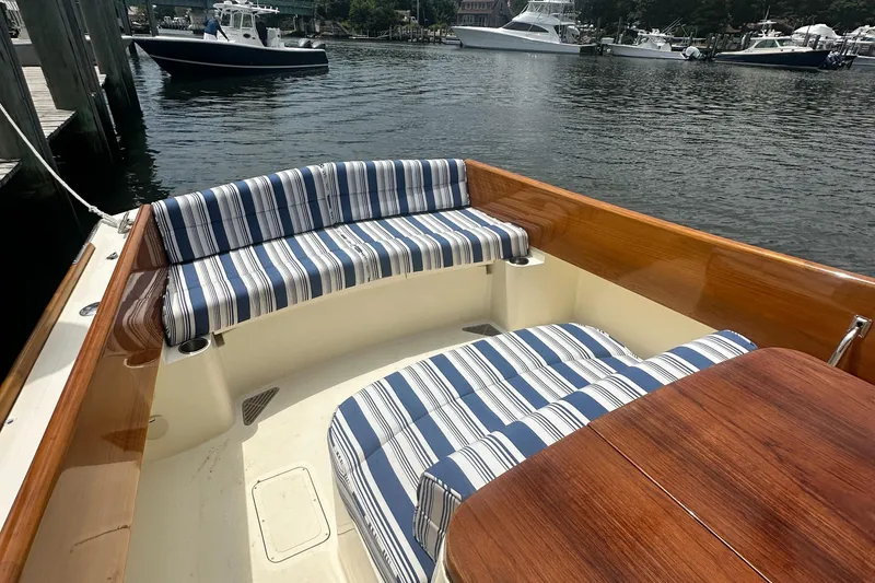 Slide: The Image of Hinckley 36 boat interior with striped seating, wooden table, docked in a marina, 2005 model. - 24