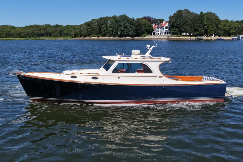 Slide: The Image of 2005 Hinckley 36 boat cruising on a serene lake with lush greenery. - 3