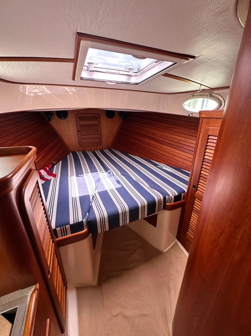 Slide: The Image of 2005 Hinckley 36 yacht cabin with striped bedding and wooden interior. - 34