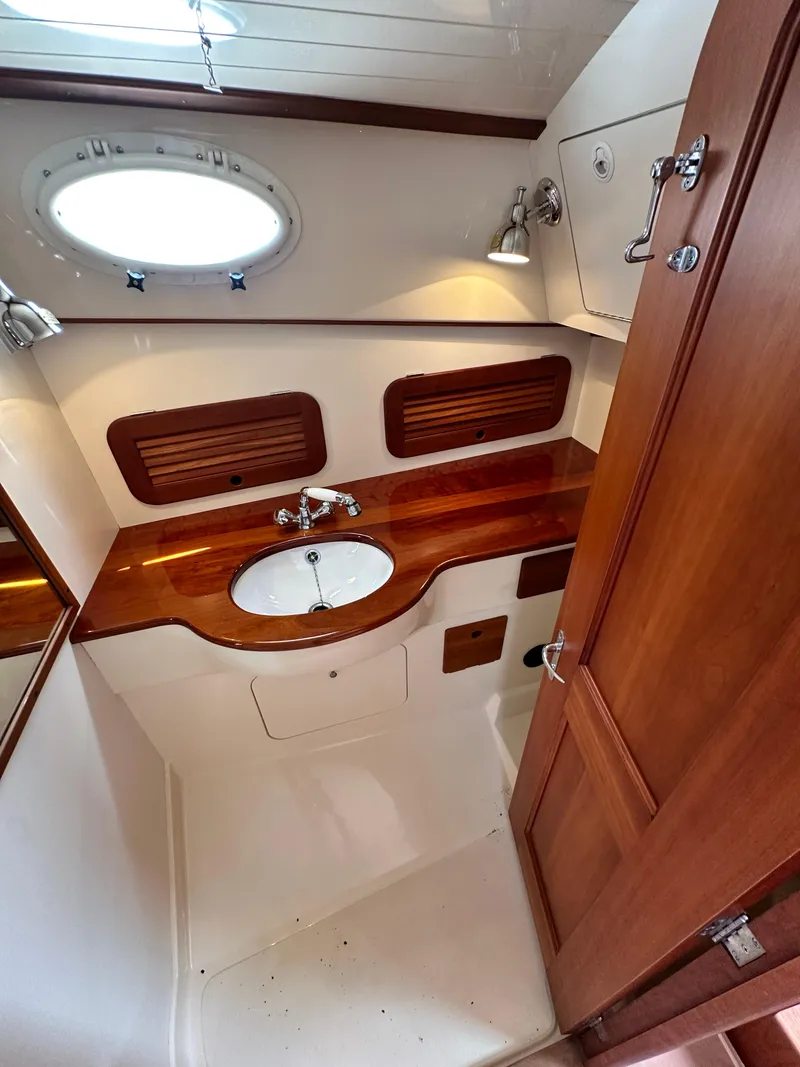 Slide: The Image of 2005 Hinckley 36 yacht bathroom with wooden countertop, sink, and porthole window. - 35