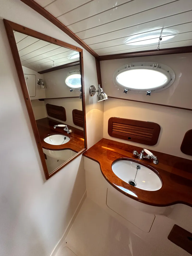 Slide: The Image of Luxurious 2005 Hinckley 36 yacht bathroom with wooden vanity and oval porthole window. - 36