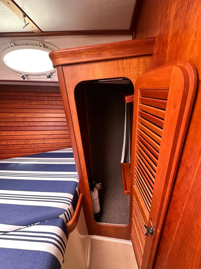 Slide: The Image of Interior of 2005 Hinckley 36 boat with wooden paneling and striped bedding. - 38