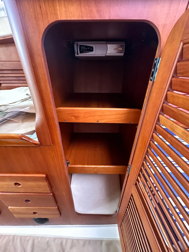 Slide: The Image of Wooden cabinet interior on a 2005 Hinckley 36 boat, featuring shelves and a small device. - 39