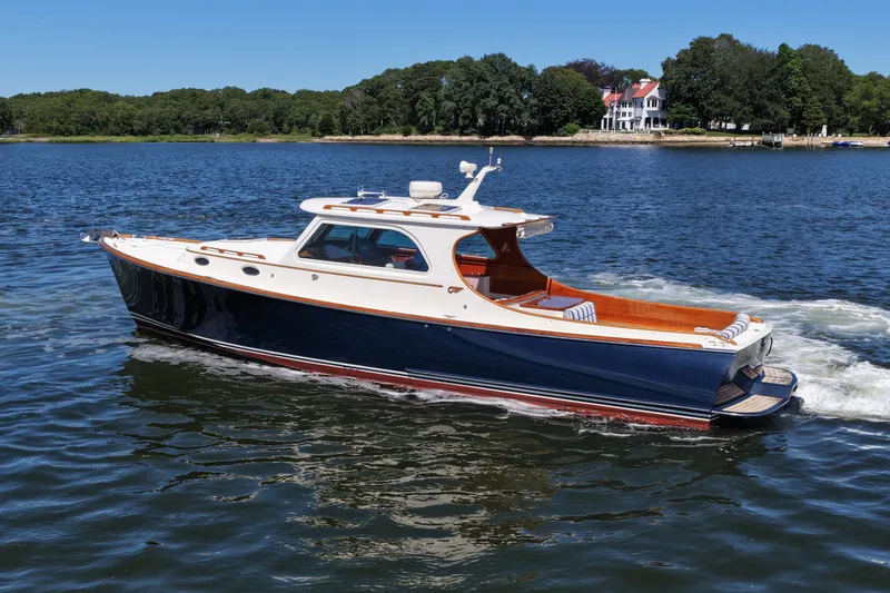 Slide: The Image of 2005 Hinckley 36 yacht cruising on a serene lake with lush green shoreline. - 4