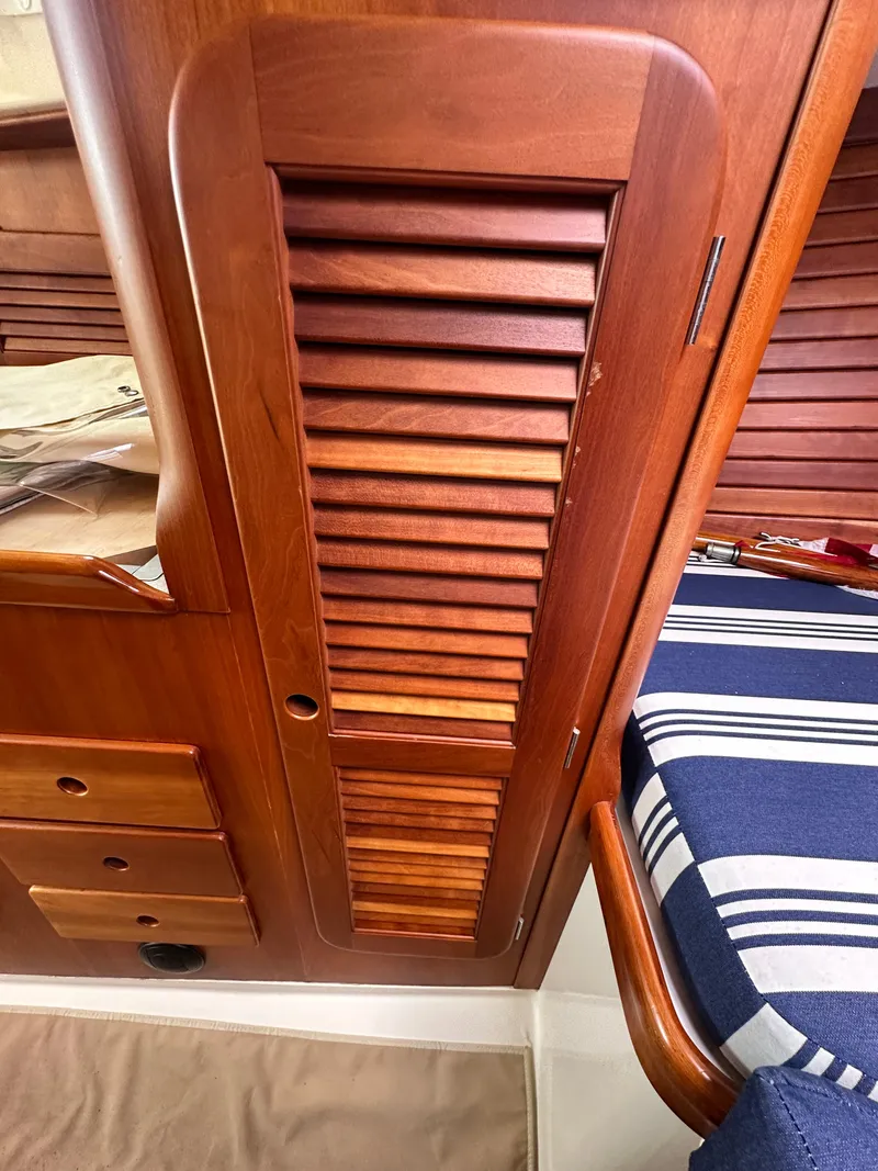Slide: The Image of Wooden interior of a 2005 Hinckley 36 boat, featuring louvered cabinet and striped cushion. - 40