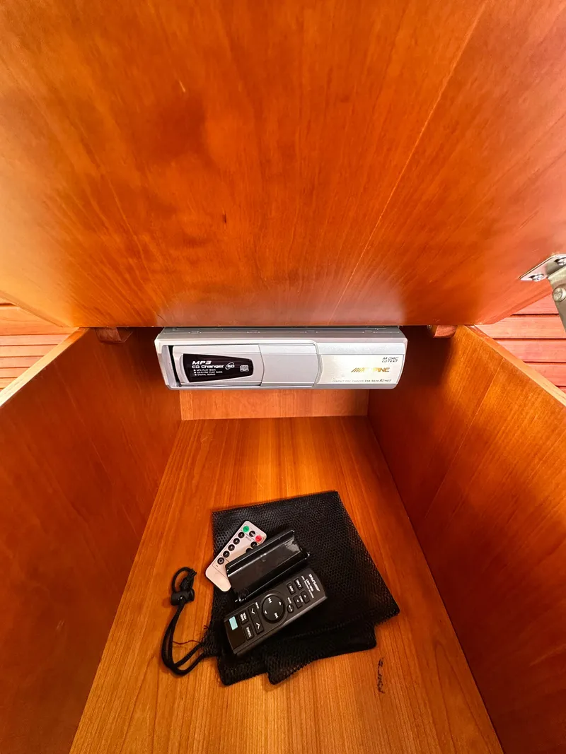 Slide: The Image of Wooden storage compartment in a 2005 Hinckley 36, containing remotes and a device. - 41