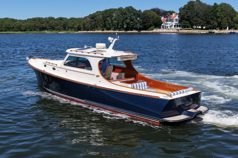 Slide: The Image of 2005 Hinckley 36 yacht cruising on a serene lake with lush greenery in the background. - 5