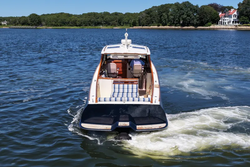 Slide: The Image of Hinckley 36 boat from 2005 cruising on a scenic lake with lush green shoreline. - 7