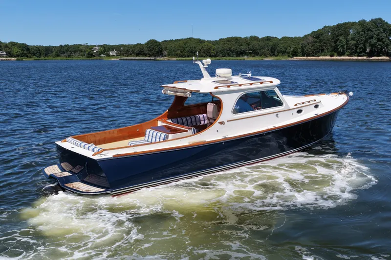 Slide: The Image of 2005 Hinckley 36 yacht cruising on a serene lake under a clear blue sky. - 9