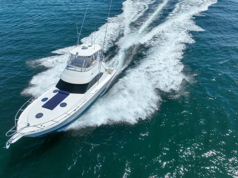 Slide: The Image of 2007 Riviera 42 Flybridge yacht cruising on open water, creating a wake. - 11