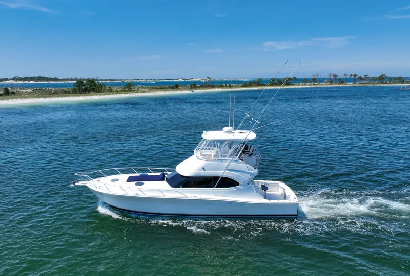 Slide: The Image of 2007 Riviera 42 Flybridge yacht cruising on blue waters near a scenic coastline. - 2