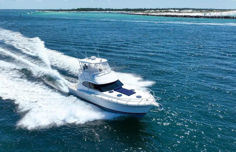 Slide: The Image of 2007 Riviera 42 Flybridge cruising on open blue waters near a sandy coastline. - 22