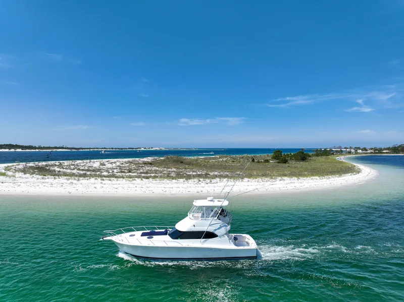Slide: The Image of 2007 Riviera 42 Flybridge yacht cruising near a scenic sandy island. - 3