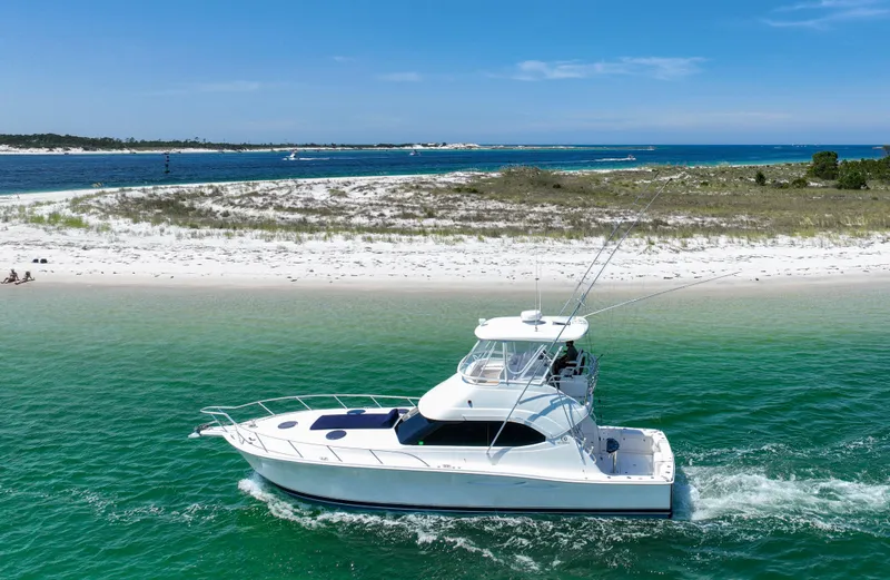 Slide: The Image of 2007 Riviera 42 Flybridge yacht cruising near a sandy beach with clear blue skies. - 4