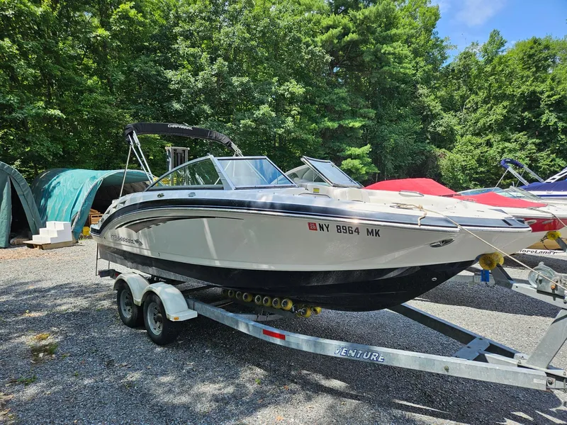 Slide: The Image of 2014 Chaparral 224 Sunesta boat on trailer, parked outdoors with trees in background. - 1