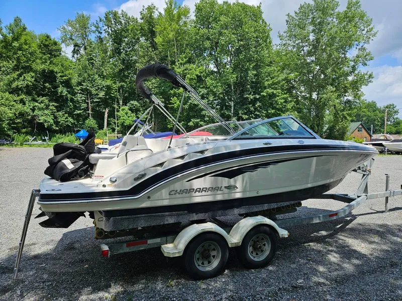 Slide: The Image of 2014 Chaparral 224 Sunesta boat on trailer, parked outdoors with trees in background. - 2
