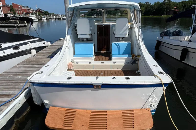 Slide: The Image of 1976 Uniflite 28 Salty Dog boat docked, featuring open deck and seating, in a marina setting. - 2