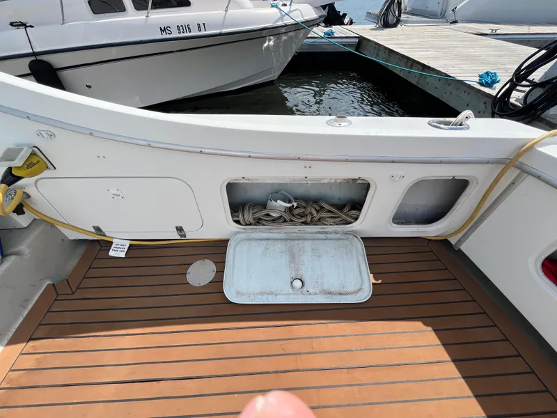 Slide: The Image of 1976 Uniflite 28 Salty Dog boat deck with storage compartment and docked vessel. - 47