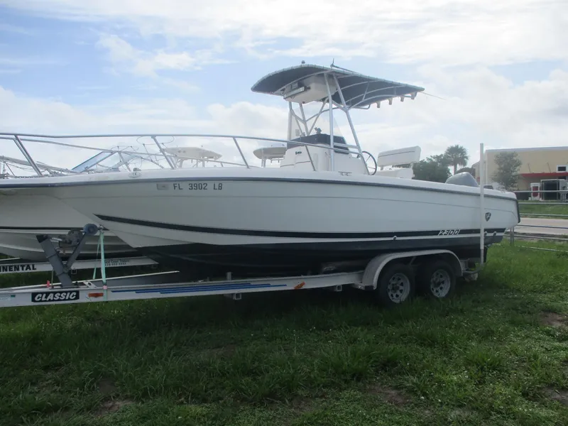 The Image of 2000 Century 2300 Center Console boat on trailer, parked on grass. - 0
