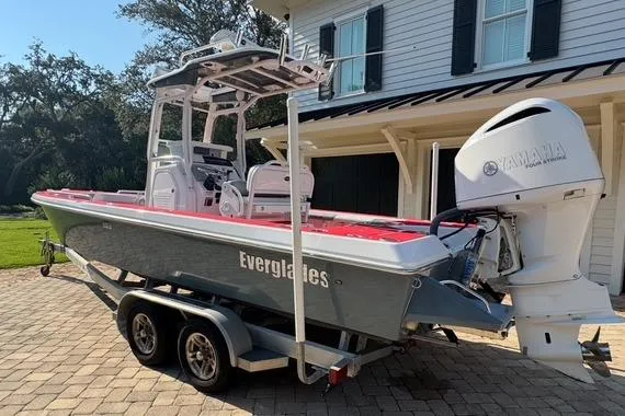 Slide: The Image of 2018 Everglades 243CC boat on trailer, parked near a house with Yamaha outboard motor. - 15
